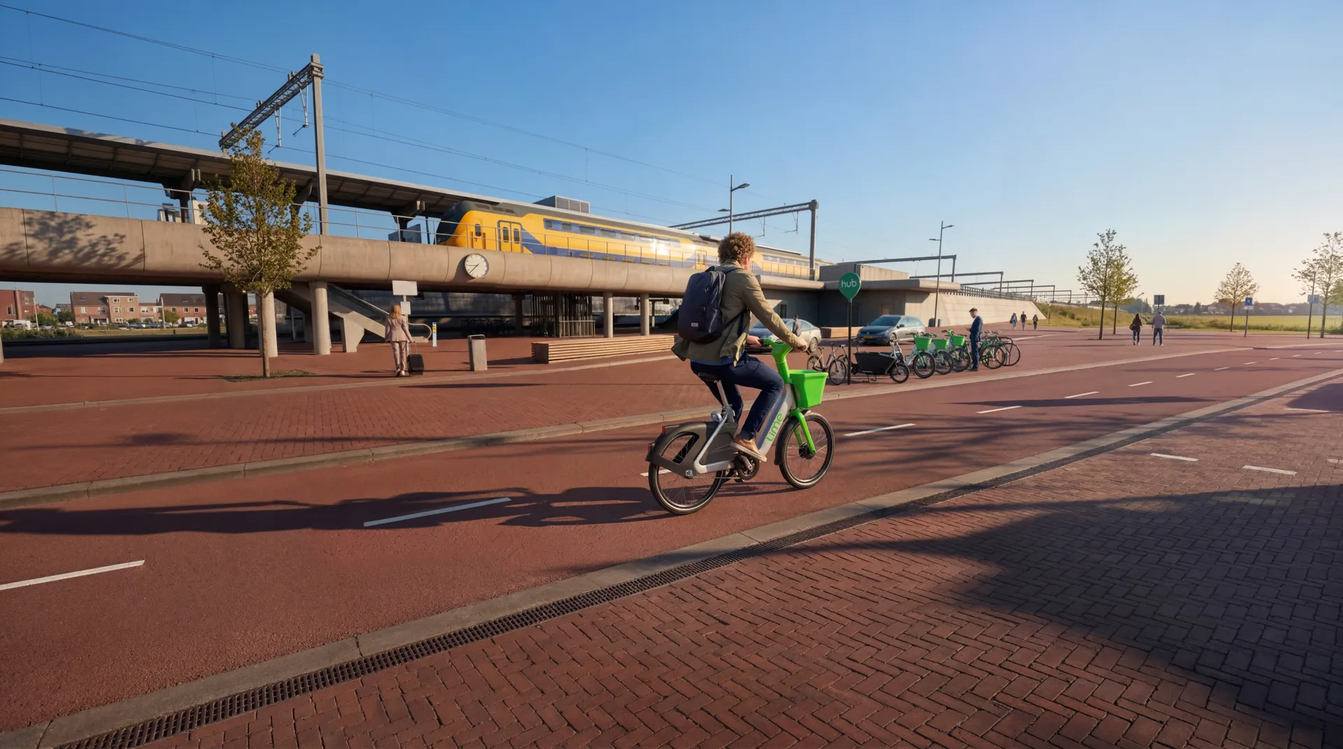 De hub met de geparkeerde groene deelfietsen. Het is een duidelijk herkenbaar deelsysteem-centrum waar meerdere fietsen staan, aangegeven door het groene ruitvormige bordje met de tekst “hub” boven een rij fietsen.