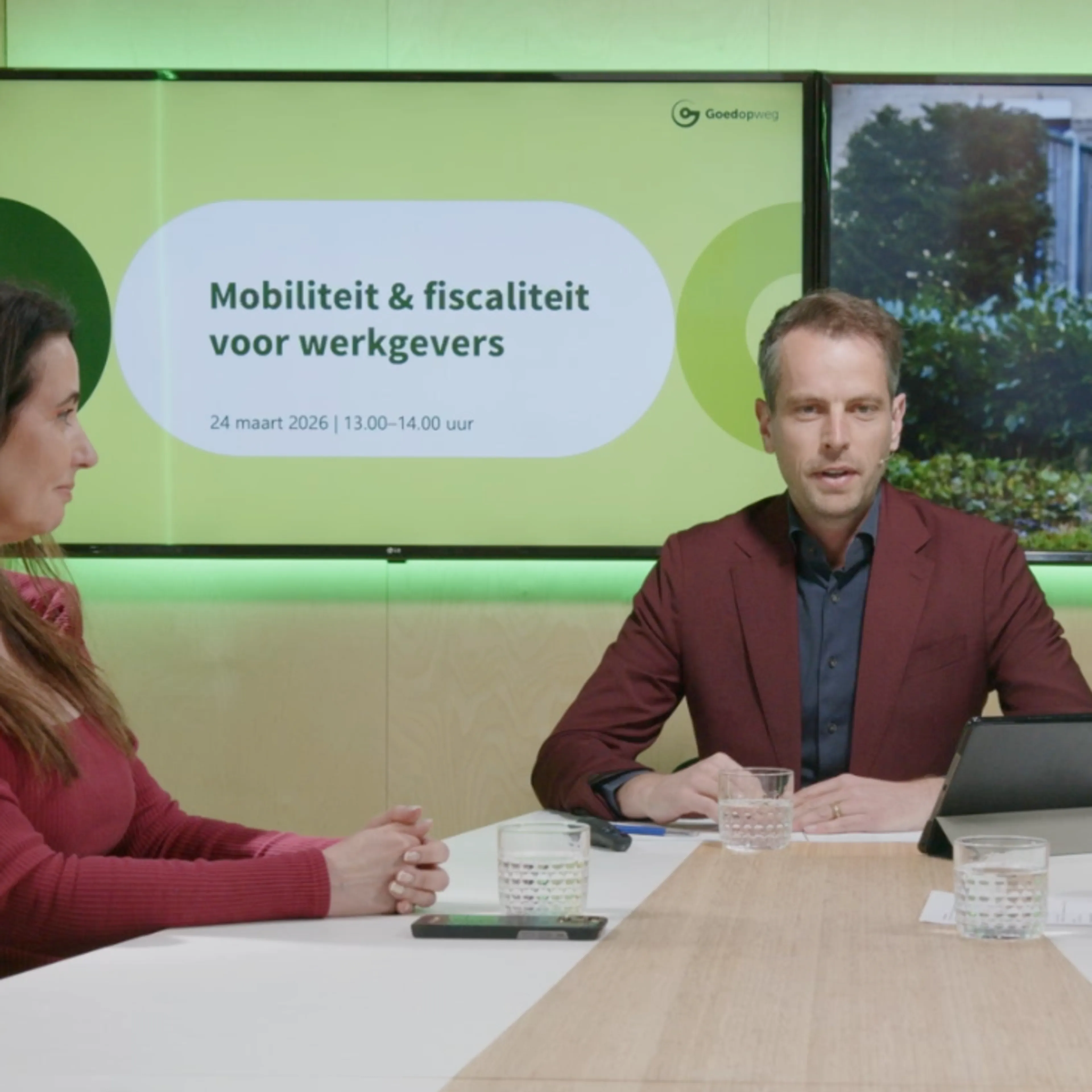 “Mobiliteit & fiscaliteit voor werkgevers” – 24 maart 2026 | 13.00 – 14.00 uur. Dit is een panel-/webinar setting in een moderne vergaderruimte met drie sprekers aan een lange tafel, begeleid door twee schermen die de mobiliteitscontext en het evenement tonen.