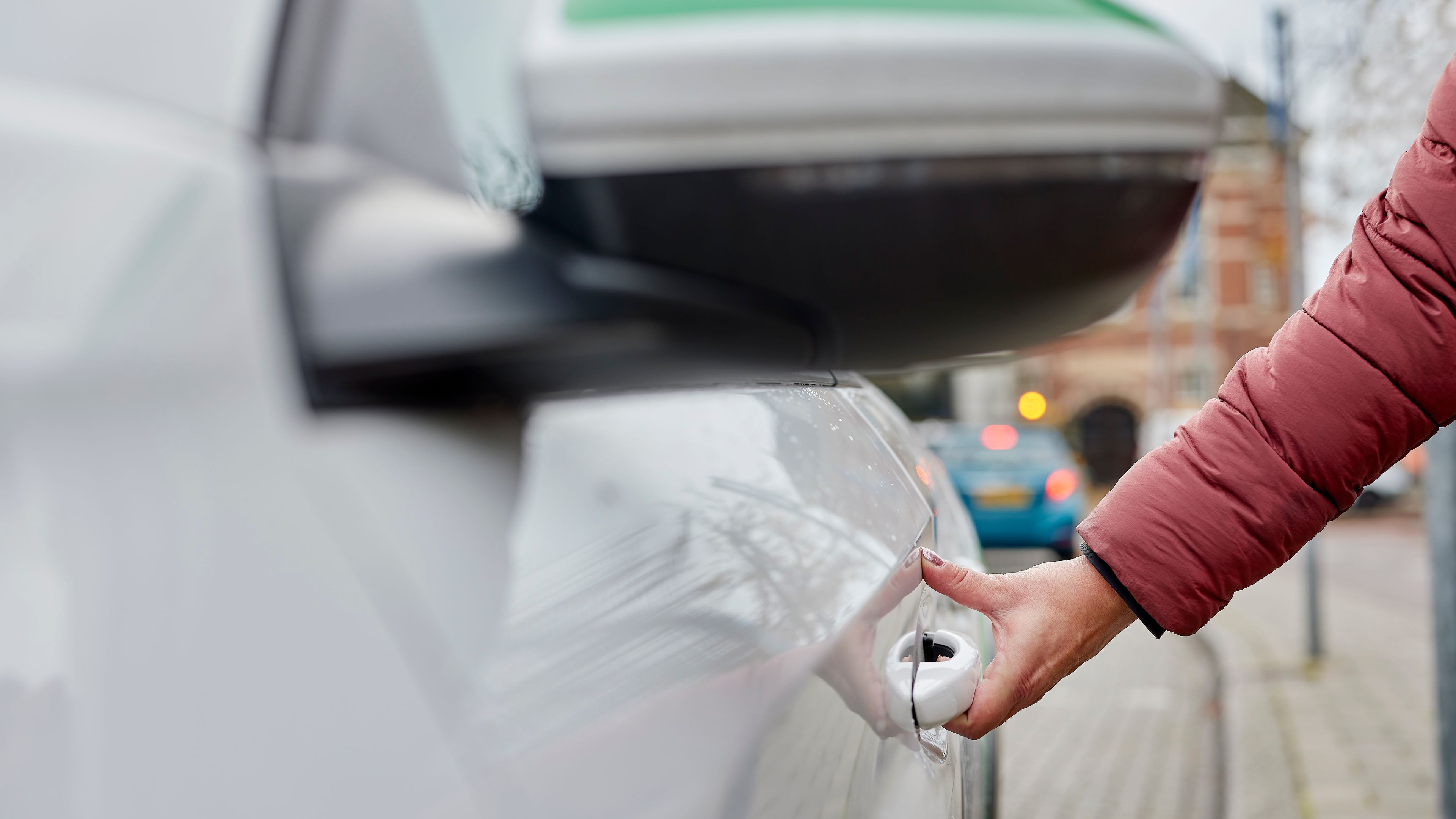 Een hand die het portier van een deelauto opent.