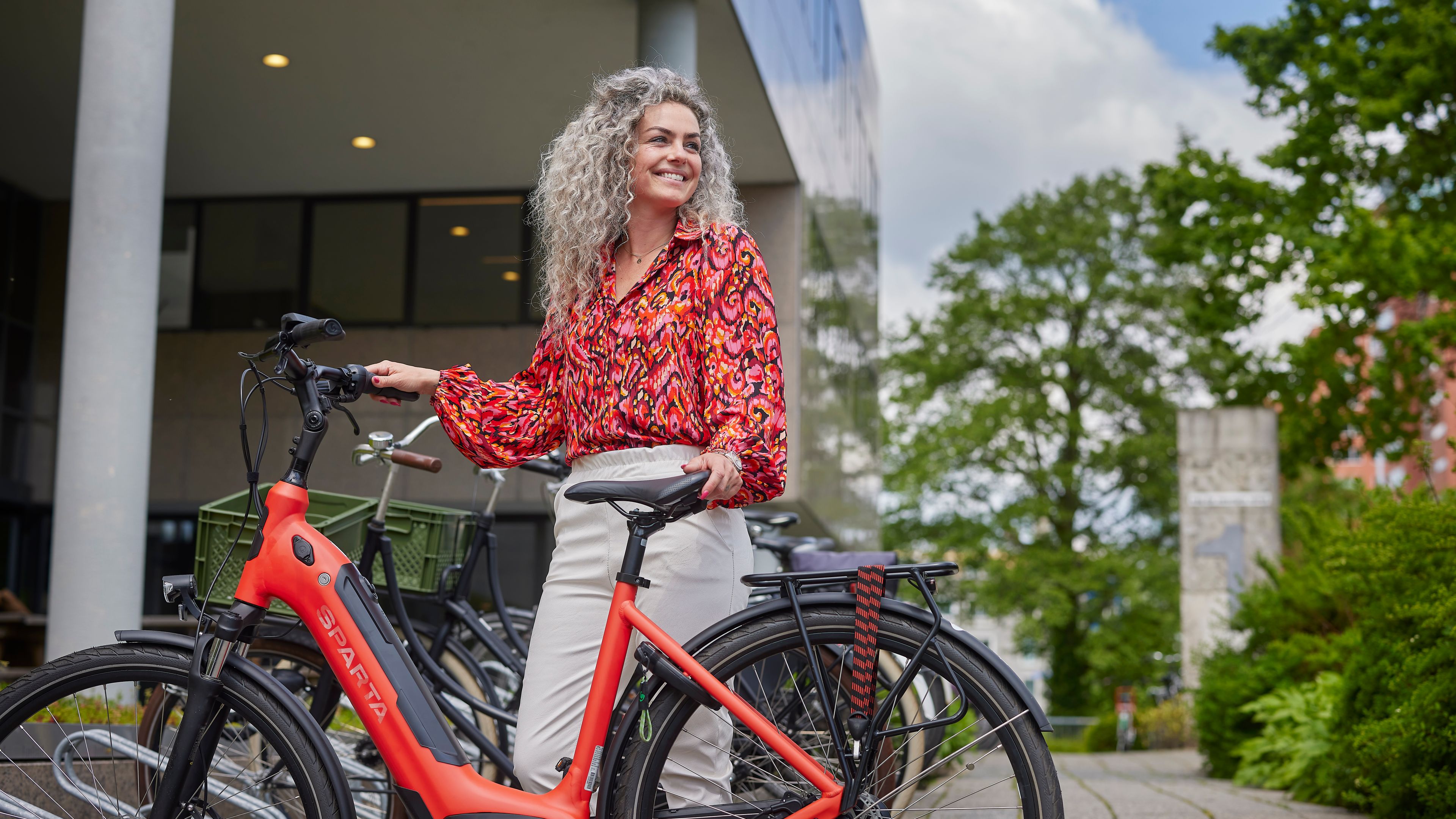 Vrouw staat met een deelfiets bij een fietsenrek.
