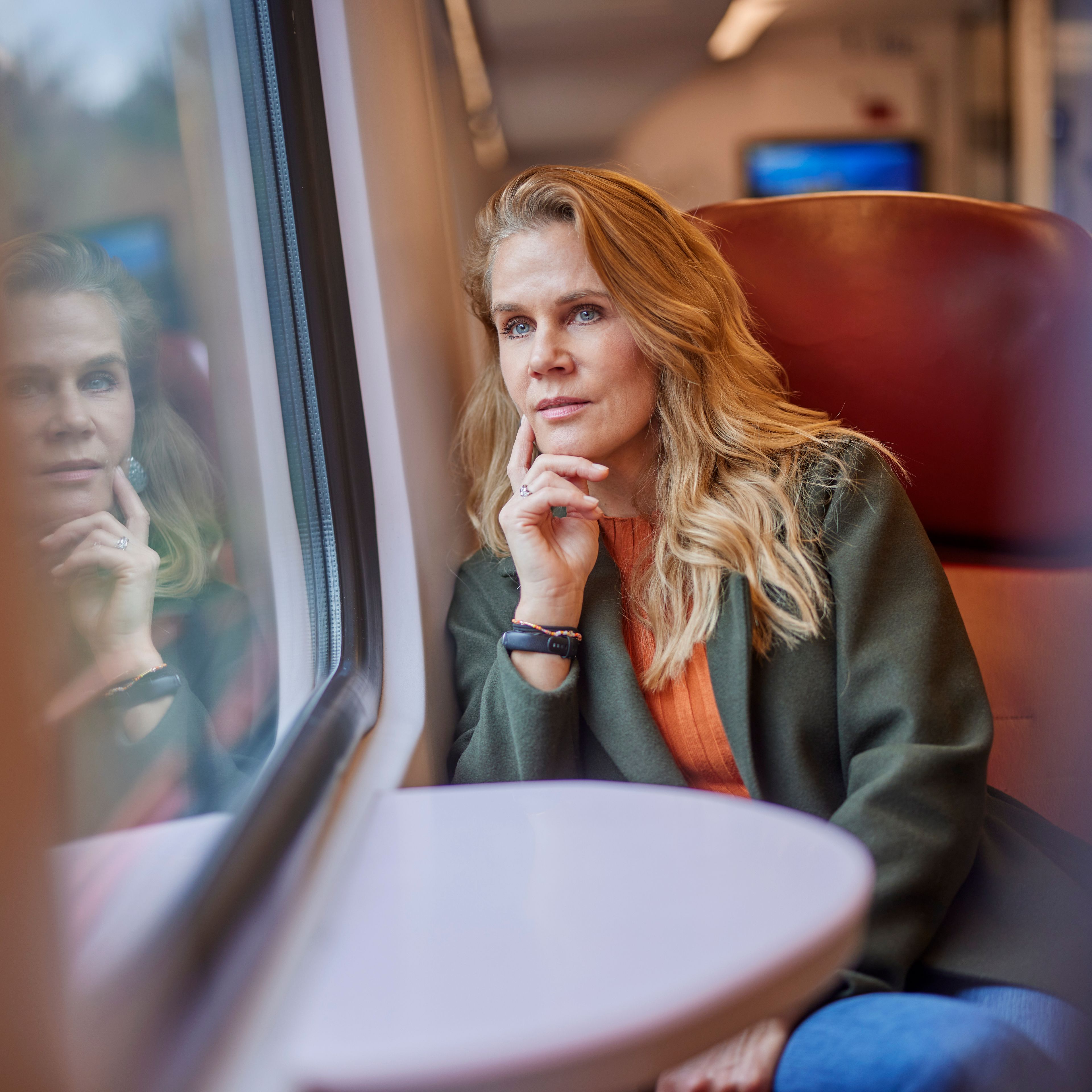 Vrouw die in de trein dromerig voor zich uit zit te staren