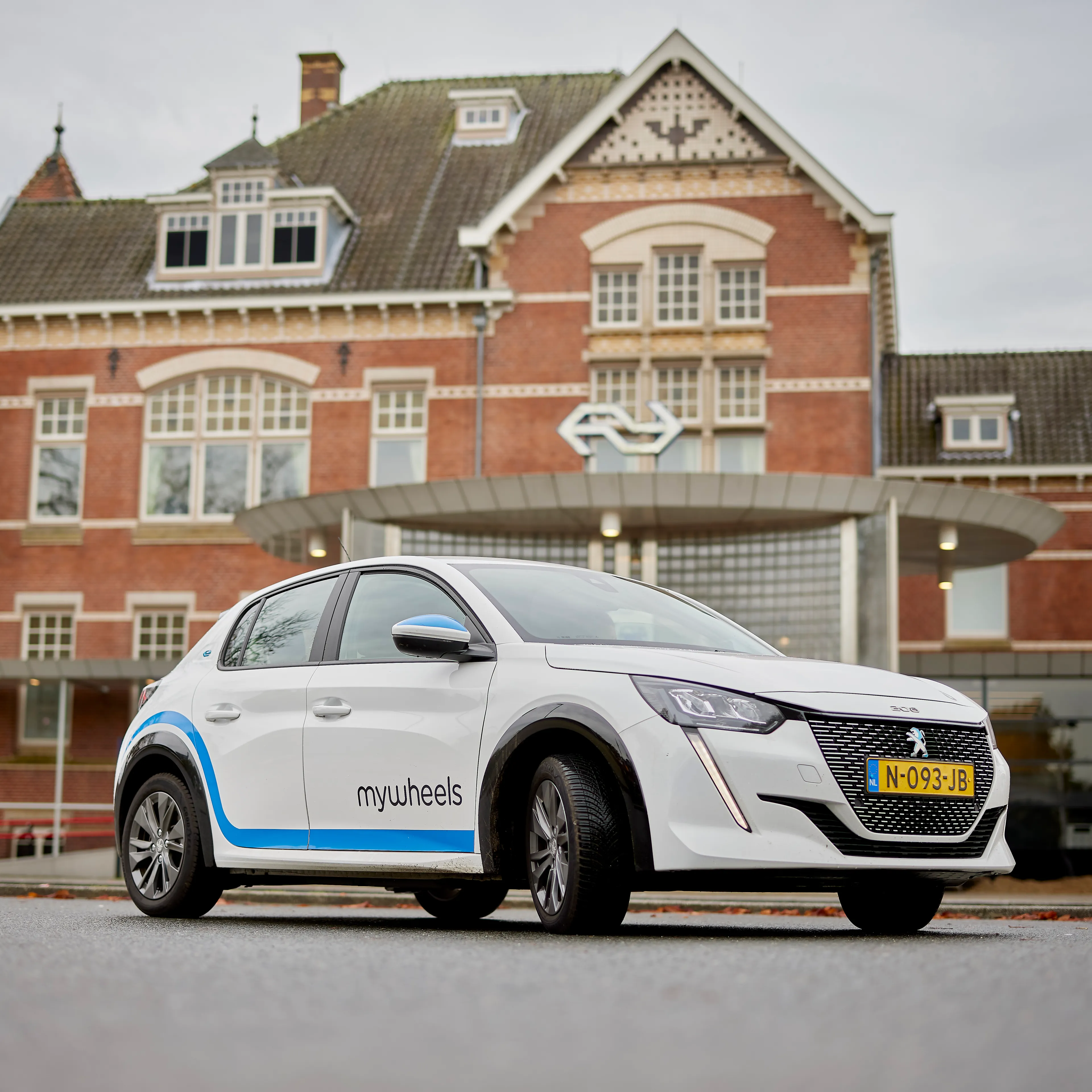 Een deelauto staat geparkeerd voor een treinstation