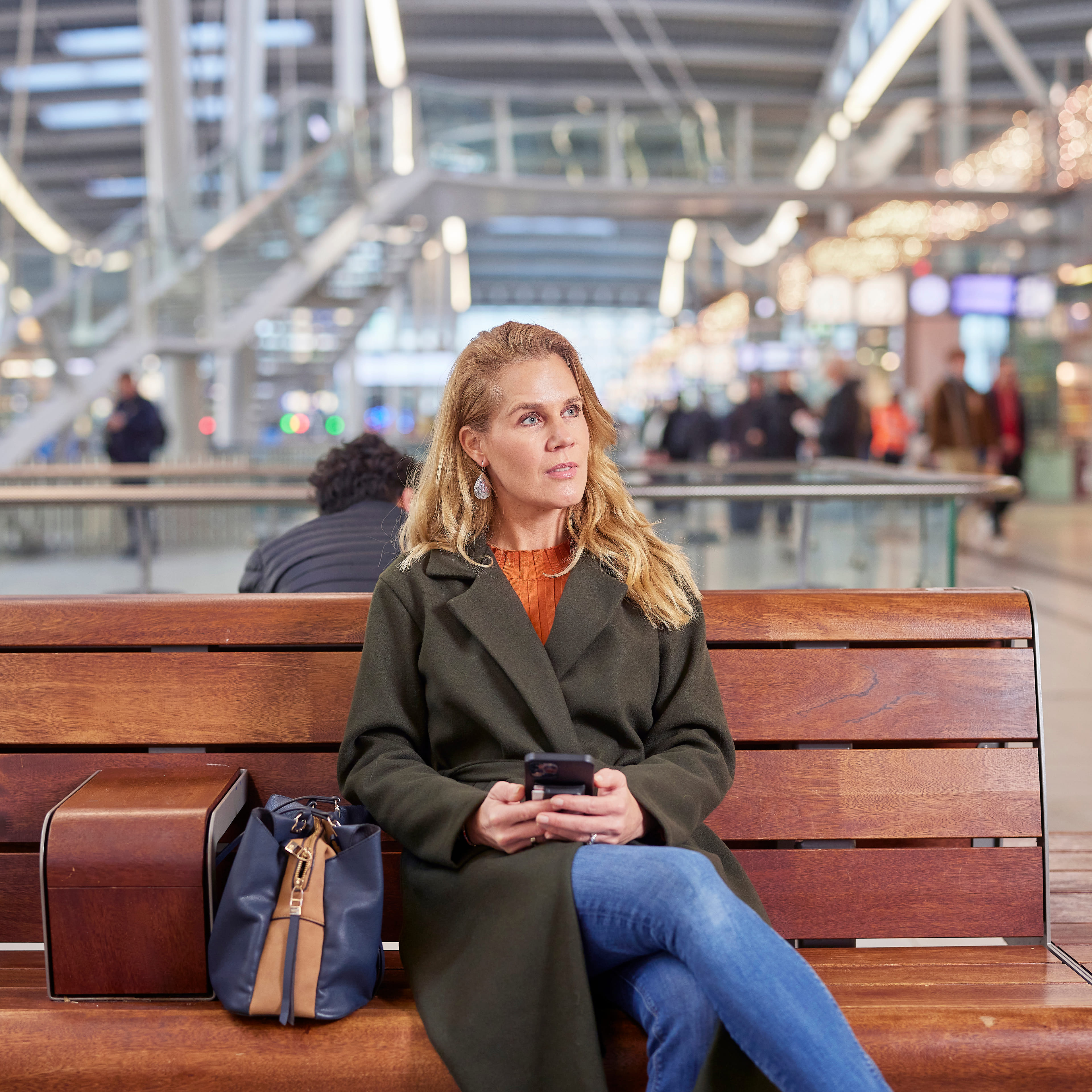 Vrouw zit op een bankje te wachten op het Centraal Station in Utrecht