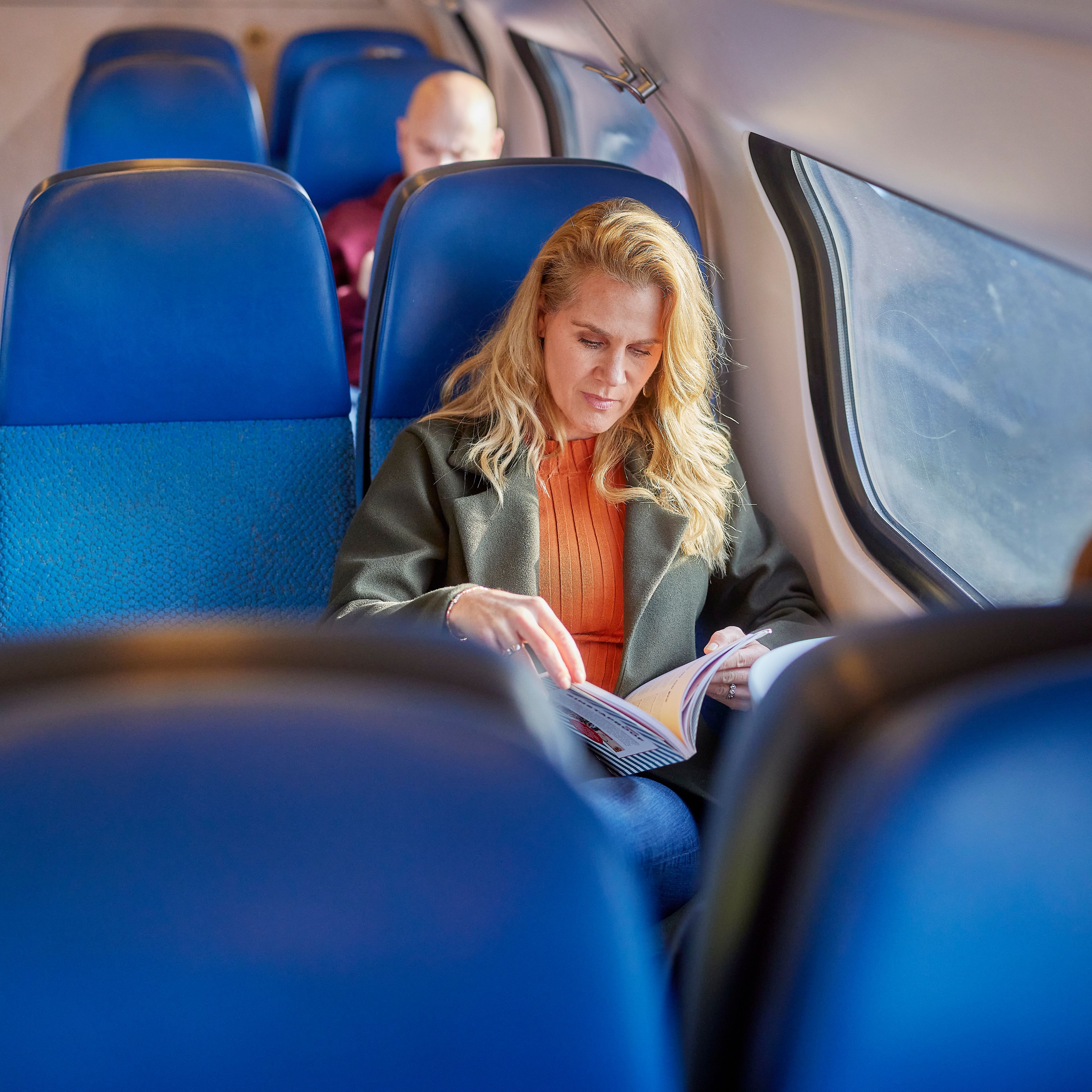 Vrouw die een boek leest in de trein.