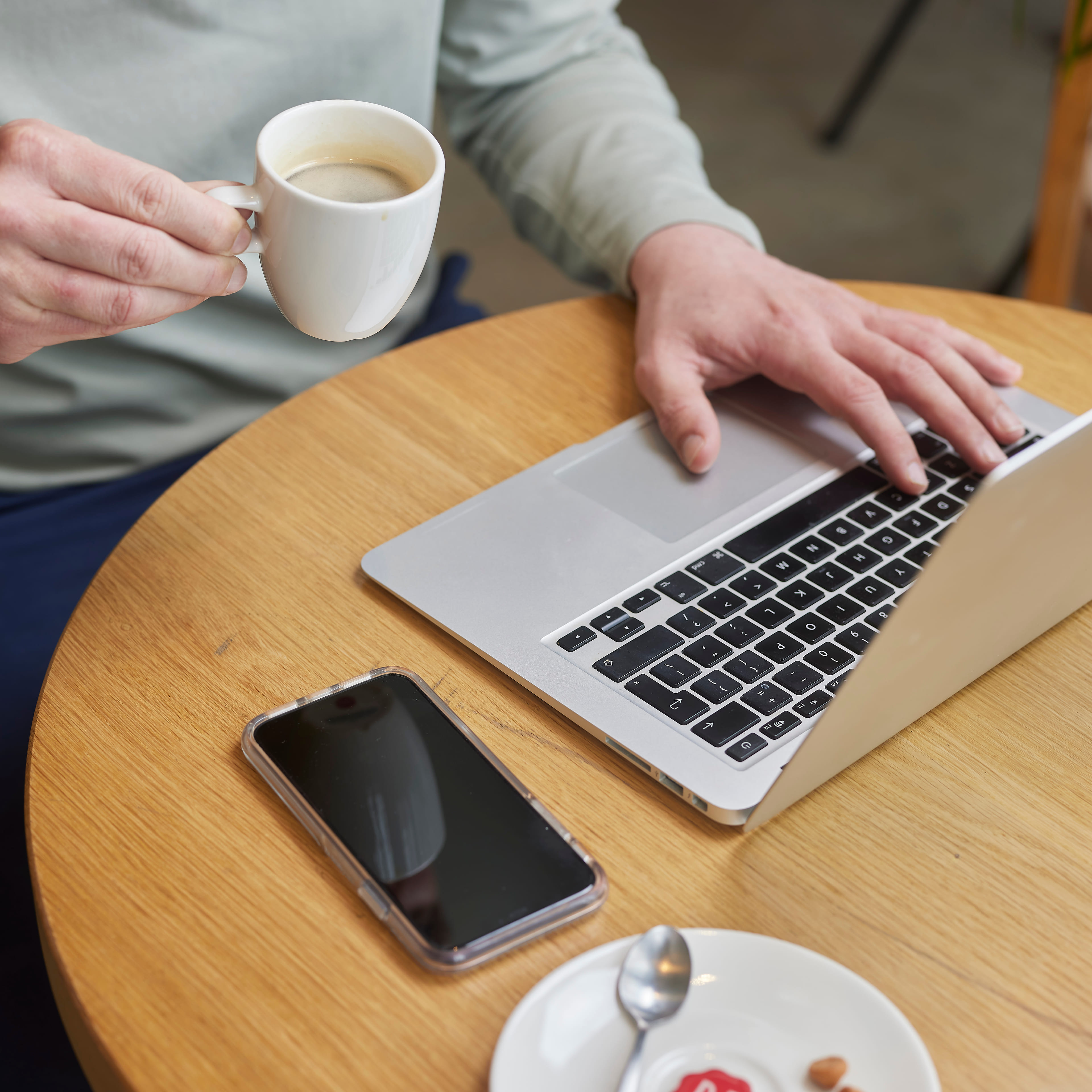 Man zit in een café te werken achter zijn laptop.