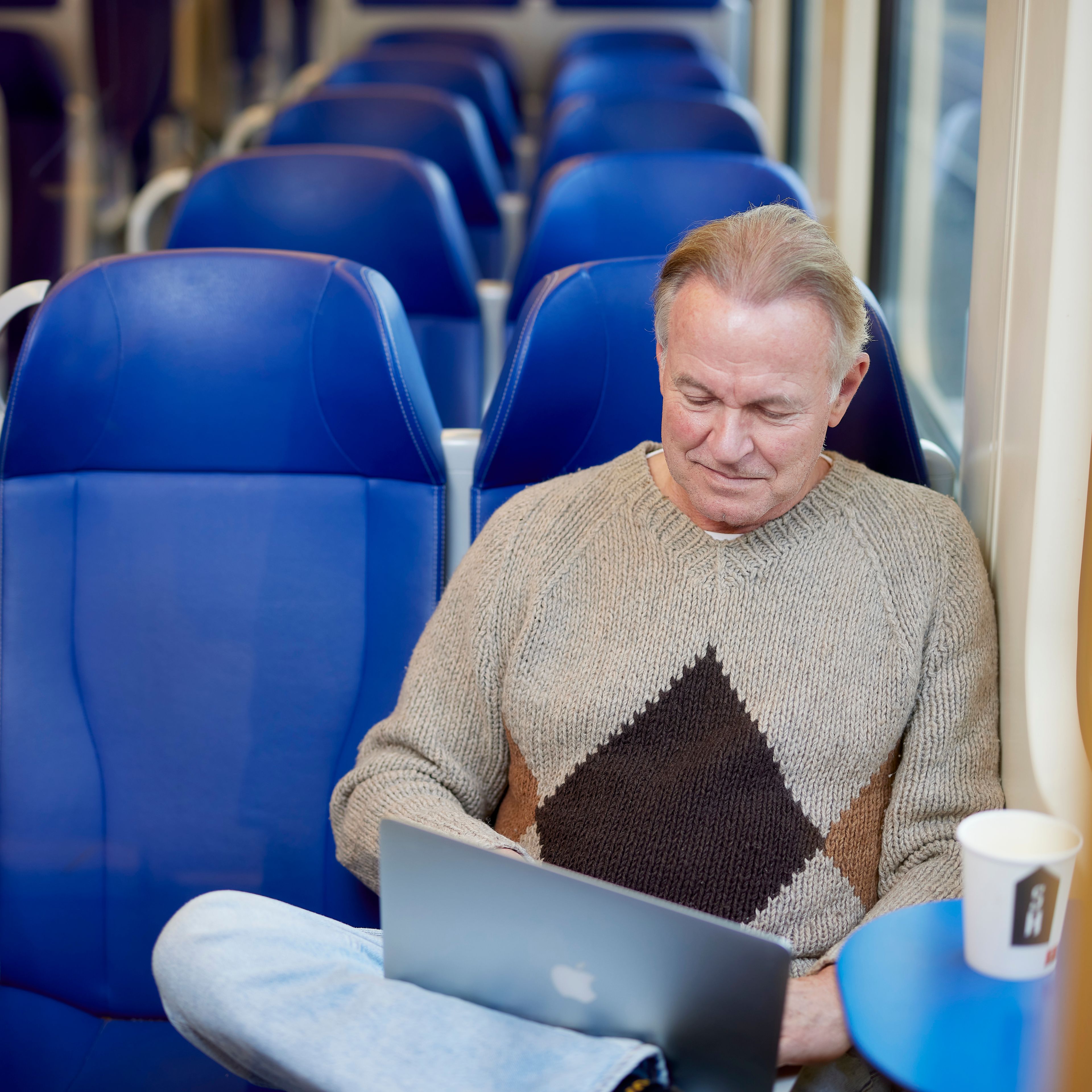 Man die op zijn laptop aan het werk is in de trein