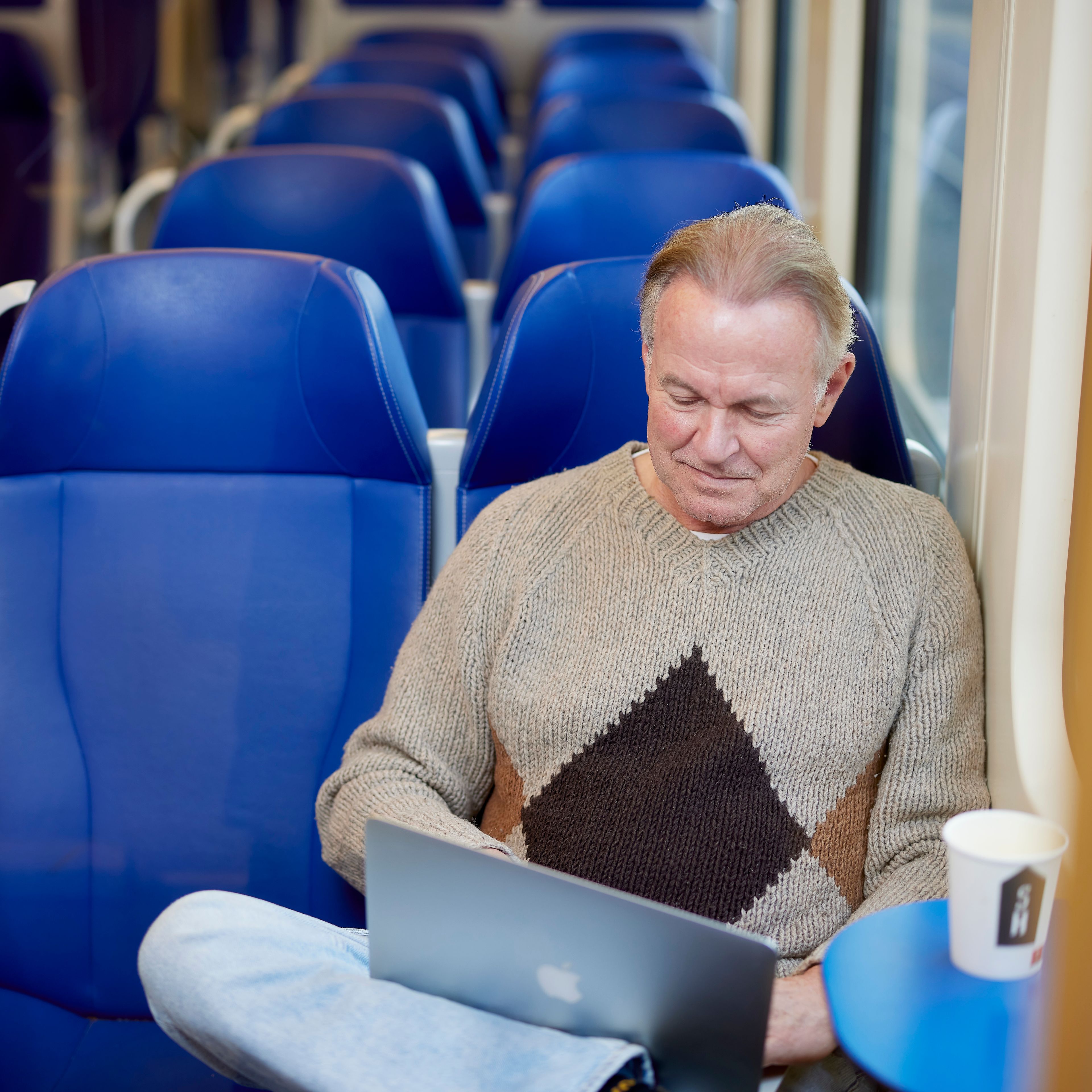 Man die op zijn laptop aan het werk is in de trein