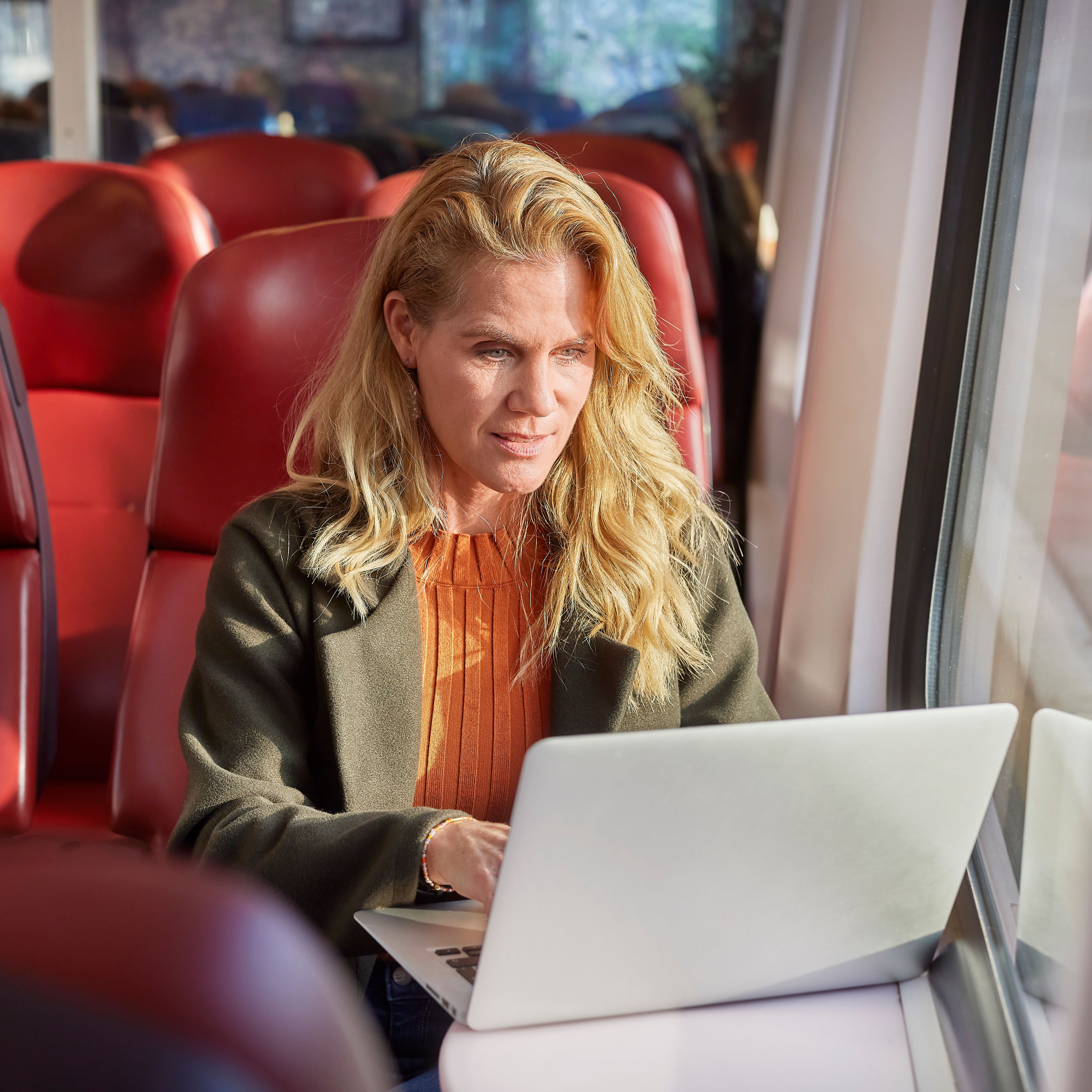 Vrouw die op een laptop aan het werk is in de trein
