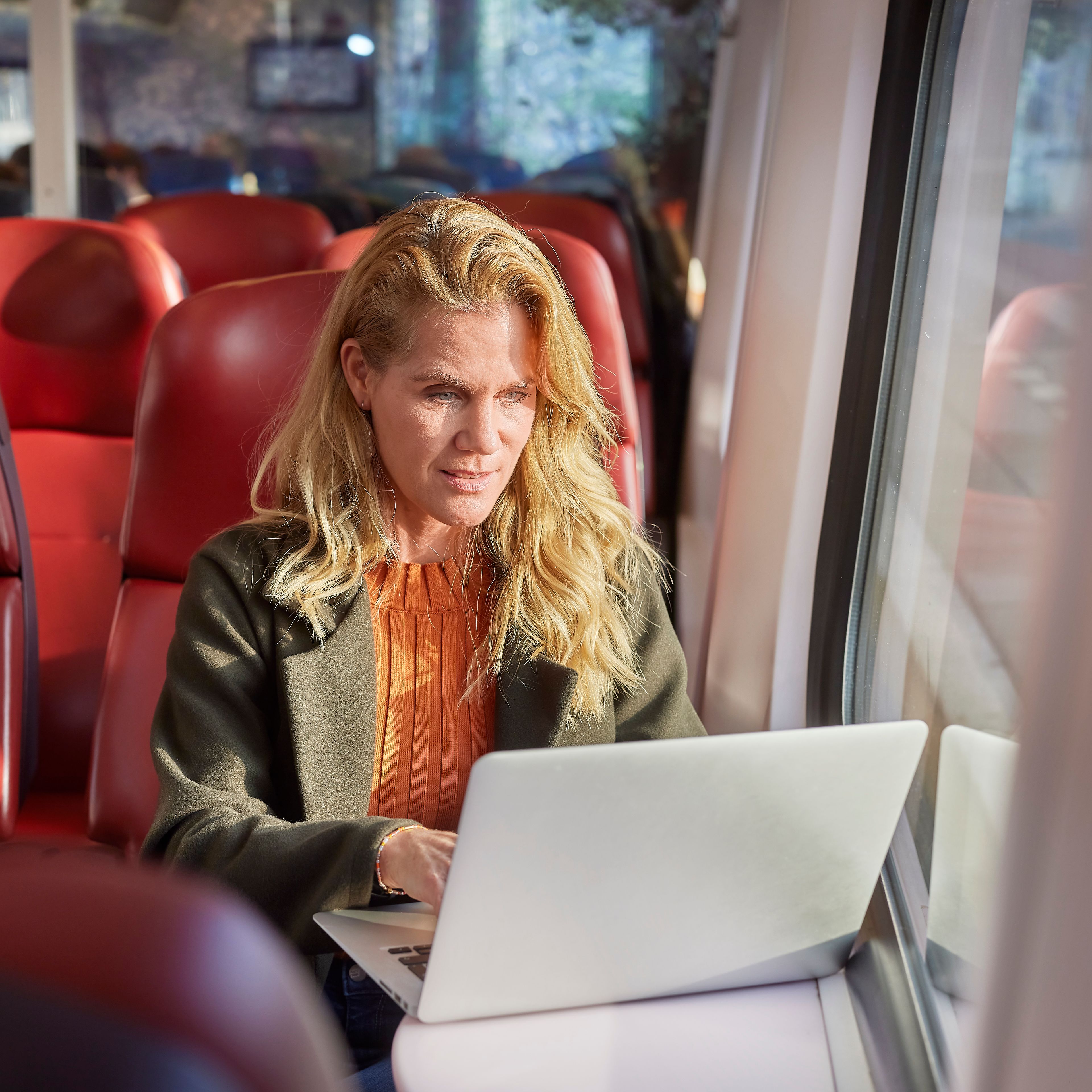 Vrouw die op een laptop aan het werk is in de trein