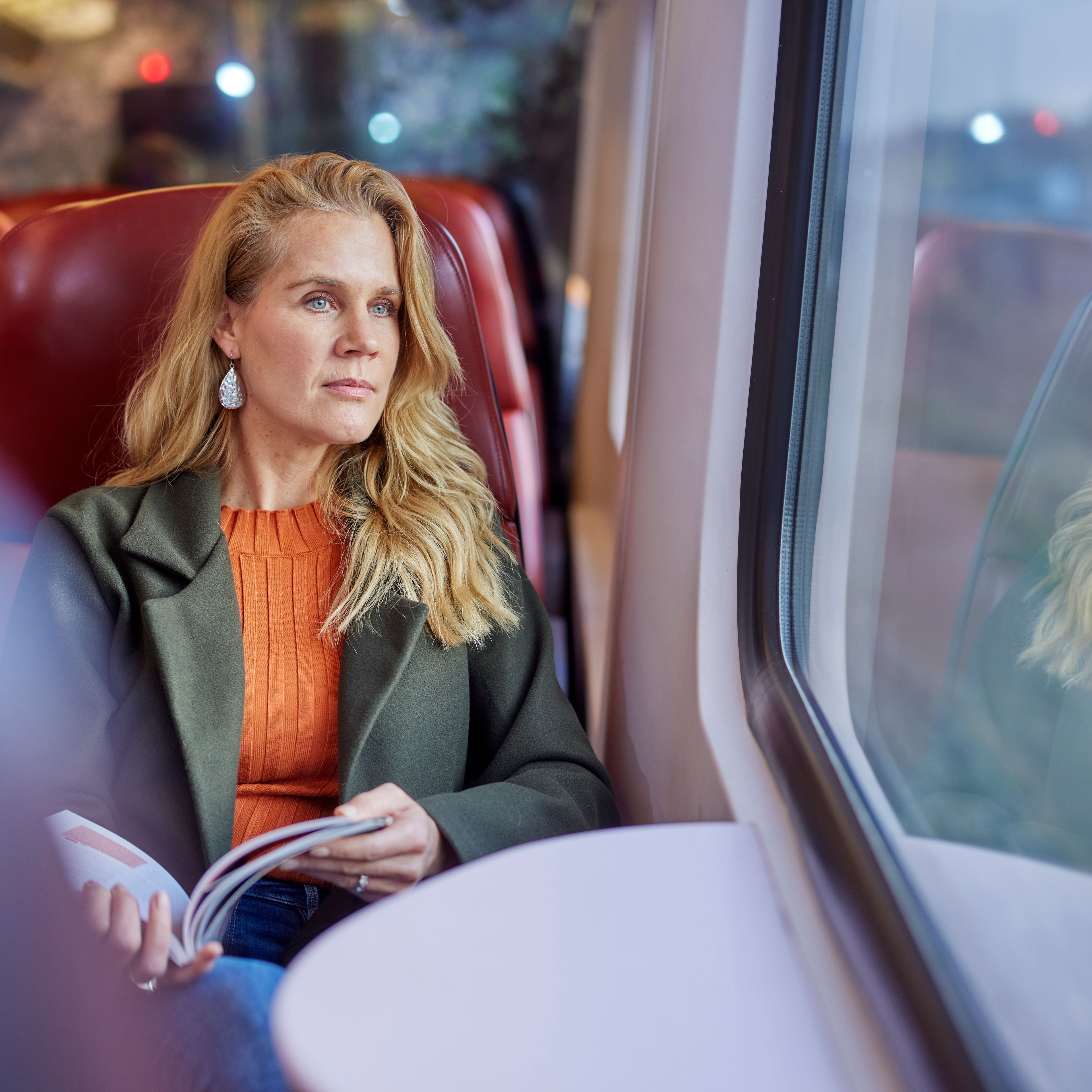 Vrouw die in de trein een boek leest en naar buiten staart
