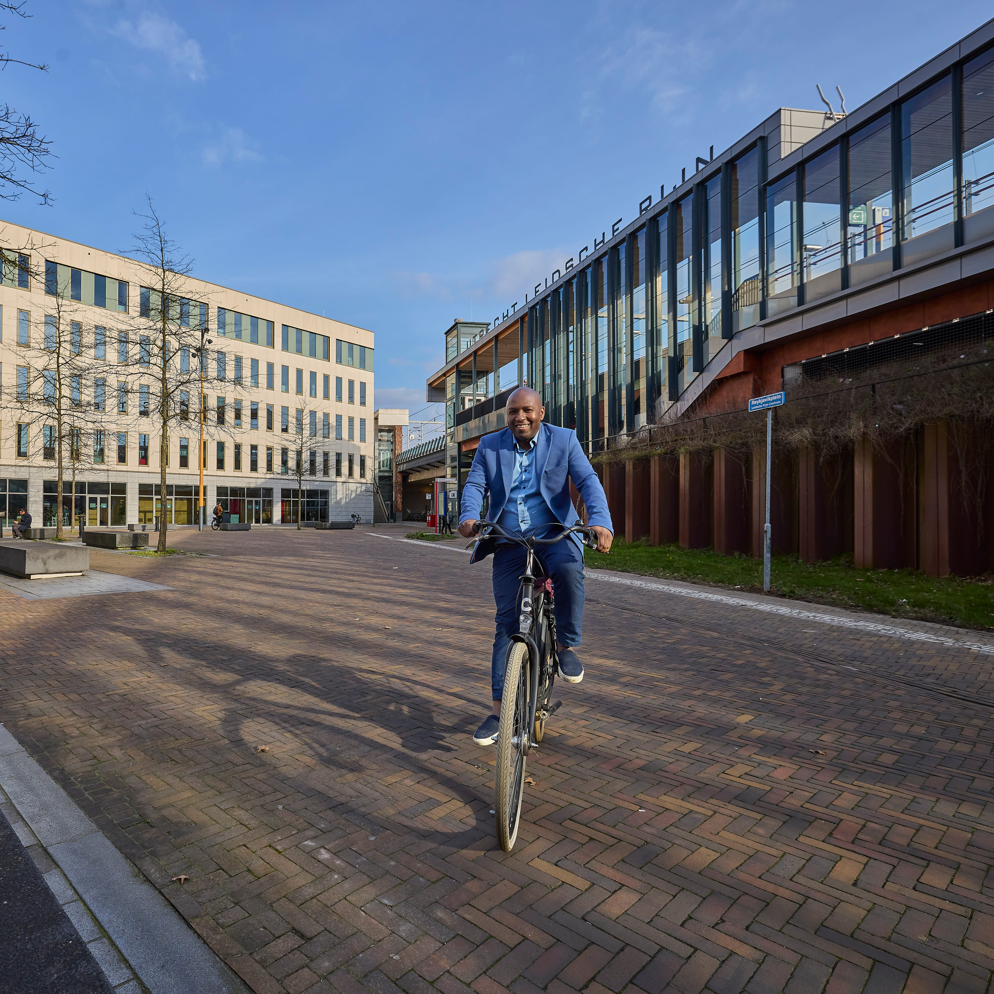 Je ziet een werknemer van Capgemini op zijn eigen fiets voorbij treinstation Leidsche Rijn fietsen.