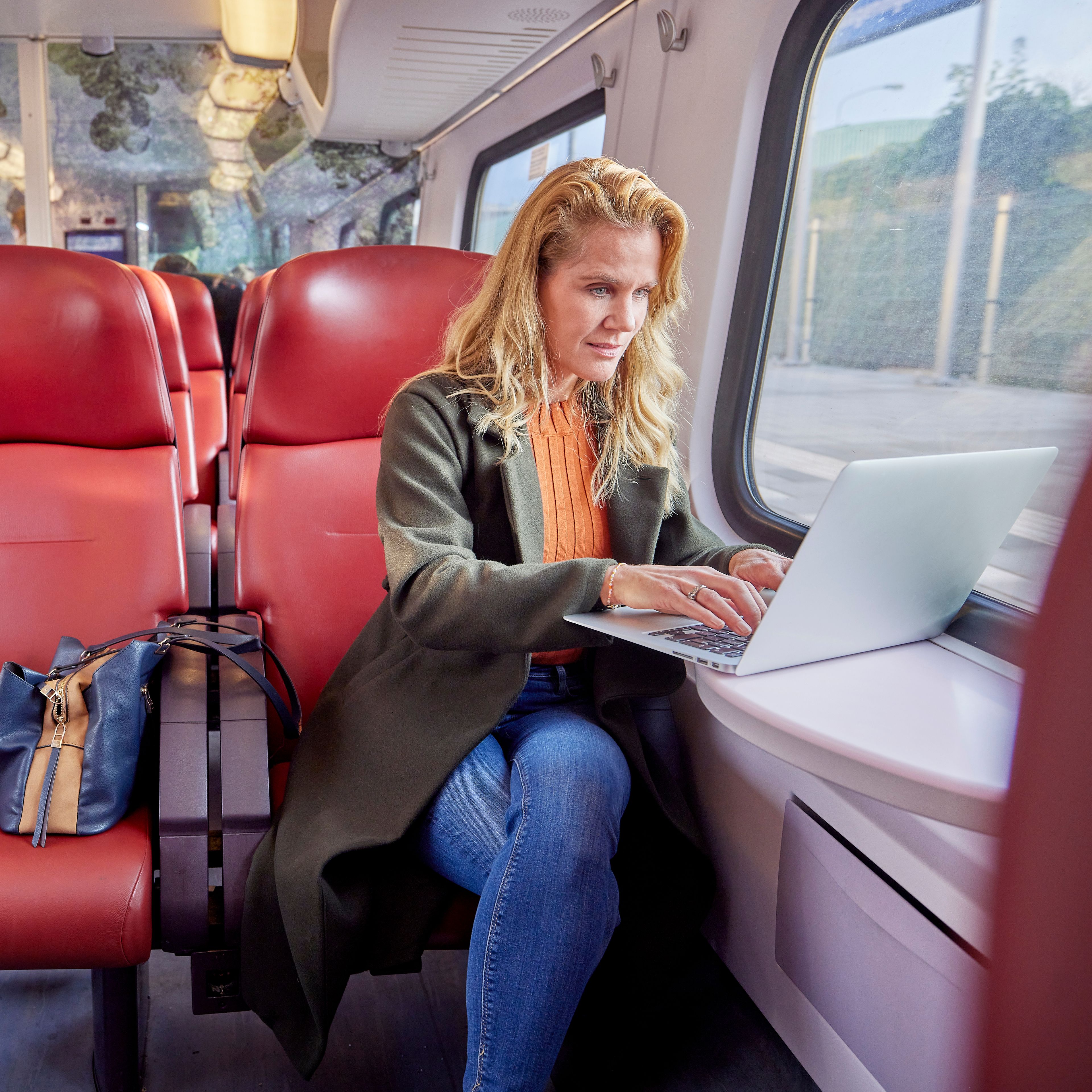 Vrouw die in de trein op haar laptop werkt