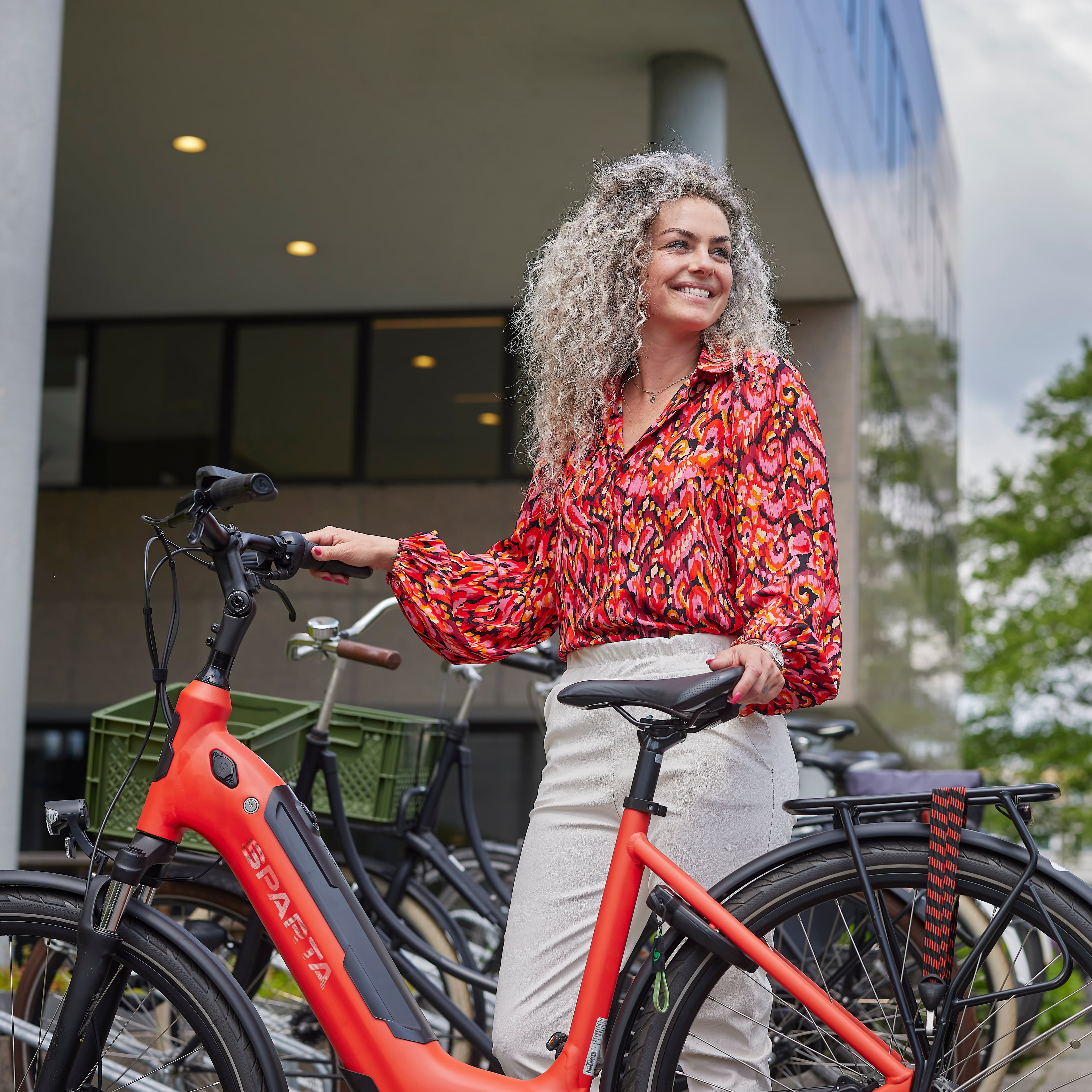 Vrouw staat met een deelfiets bij een fietsenrek.