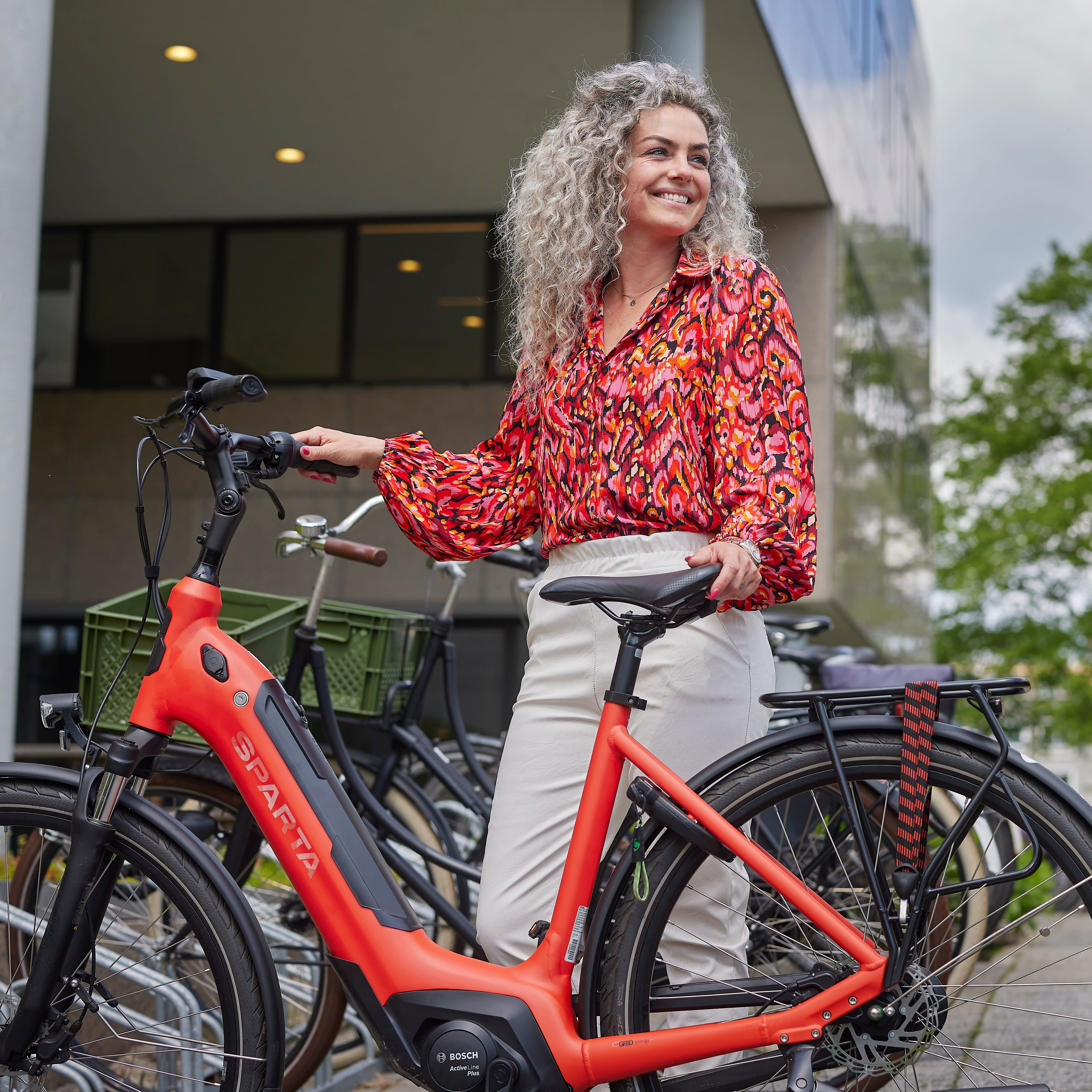 Vrouw staat met een deelfiets bij een fietsenrek.