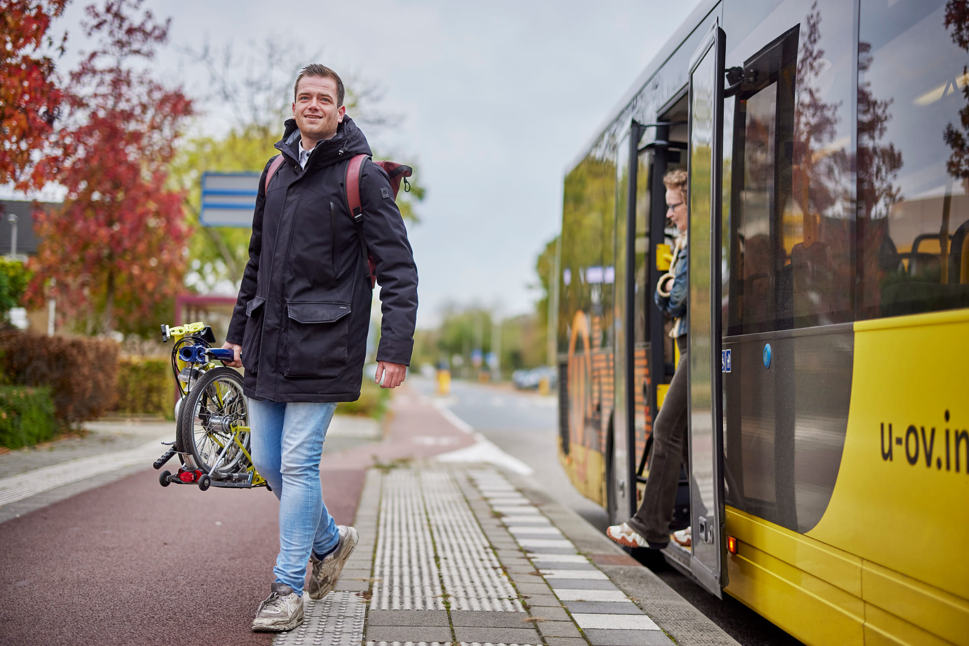 Jonge man stapt met vouwfiets uit de bus