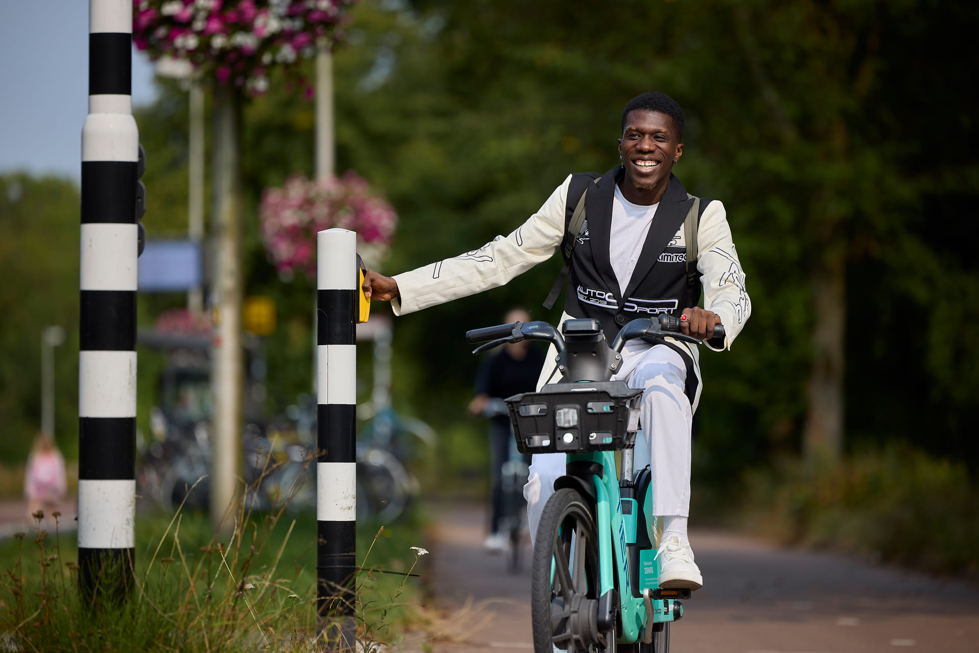 Je ziet een jonge man fietsen op een deelfiets