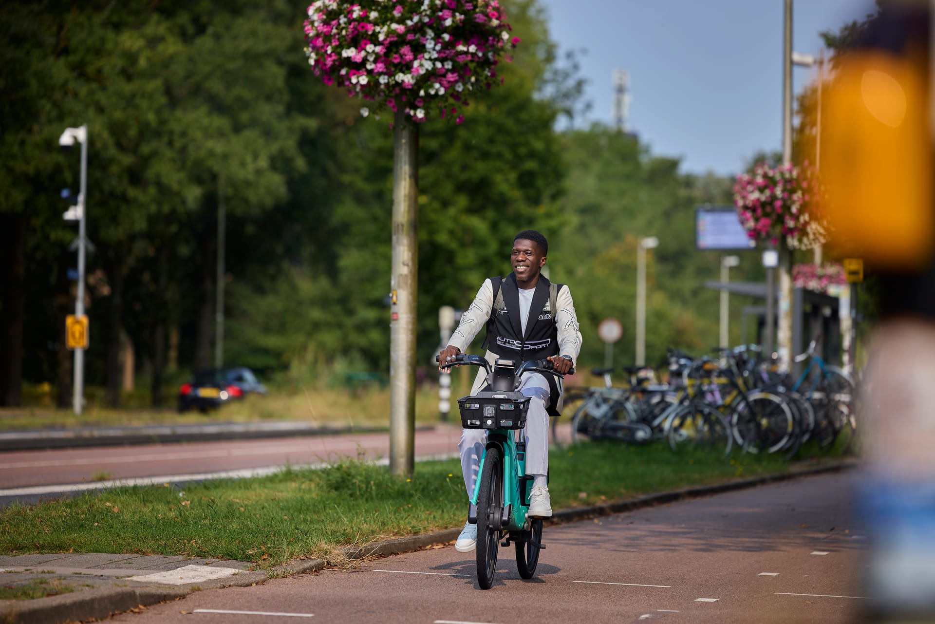 Je ziet een jonge man fietsen op een deelfiets