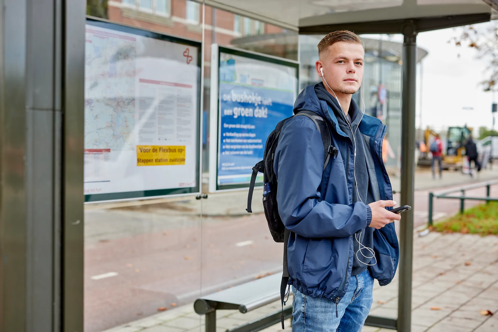 Student die bij de bushalte aan het wachten is op de bus