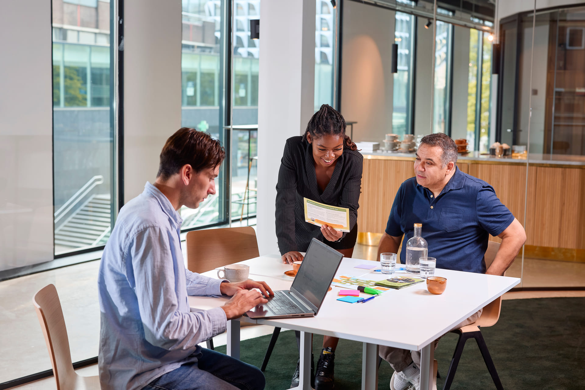 Drie collega's werken samen op kantoor. Ze lachen samen.
