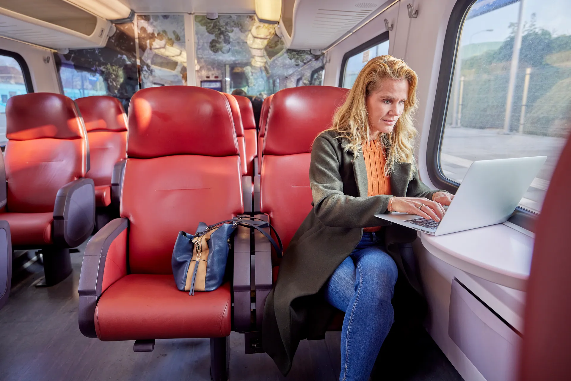 Vrouw die in de trein op haar laptop werkt