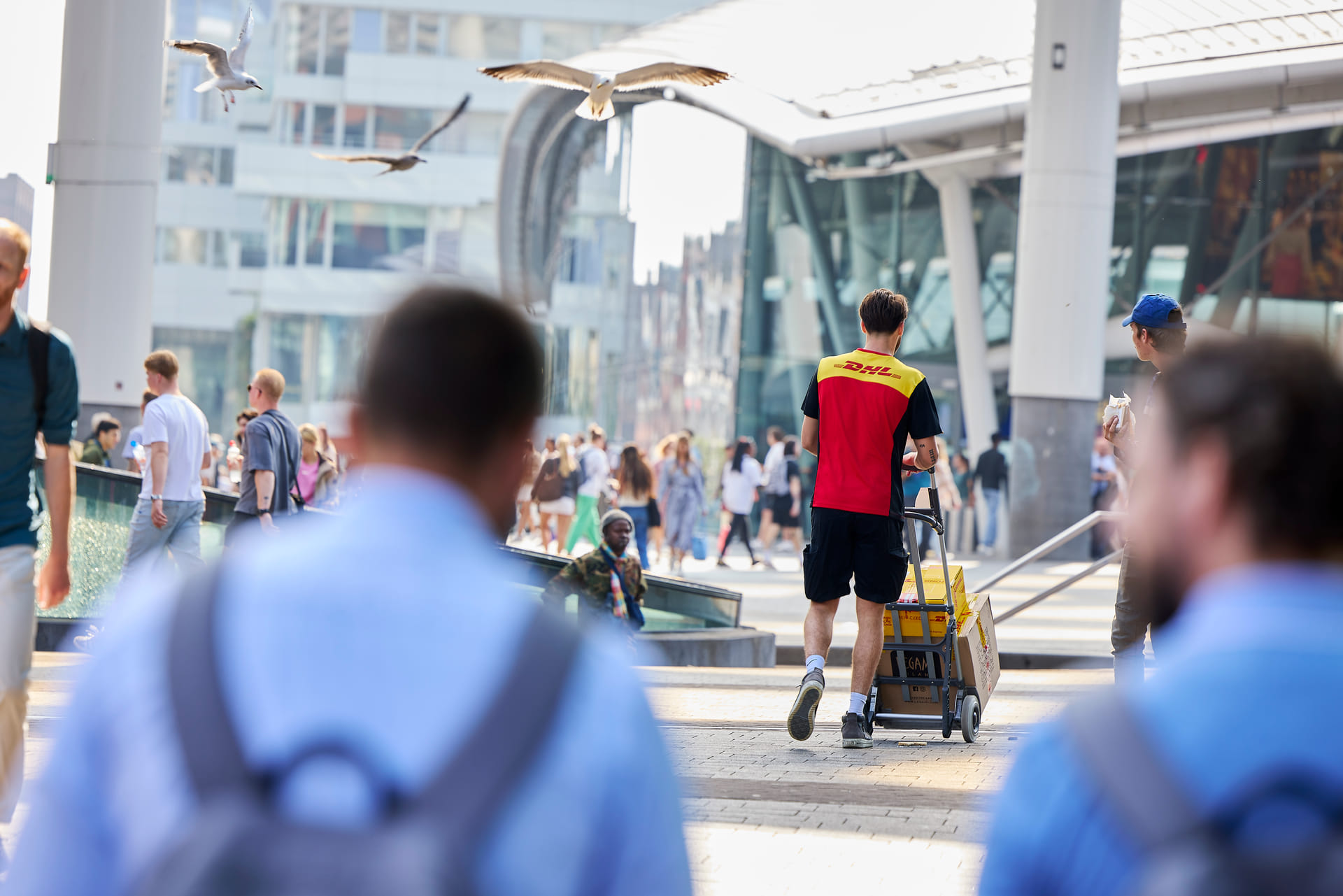 Pakketjesbezorger loopt met pakketjes richting Utrecht Centraal.