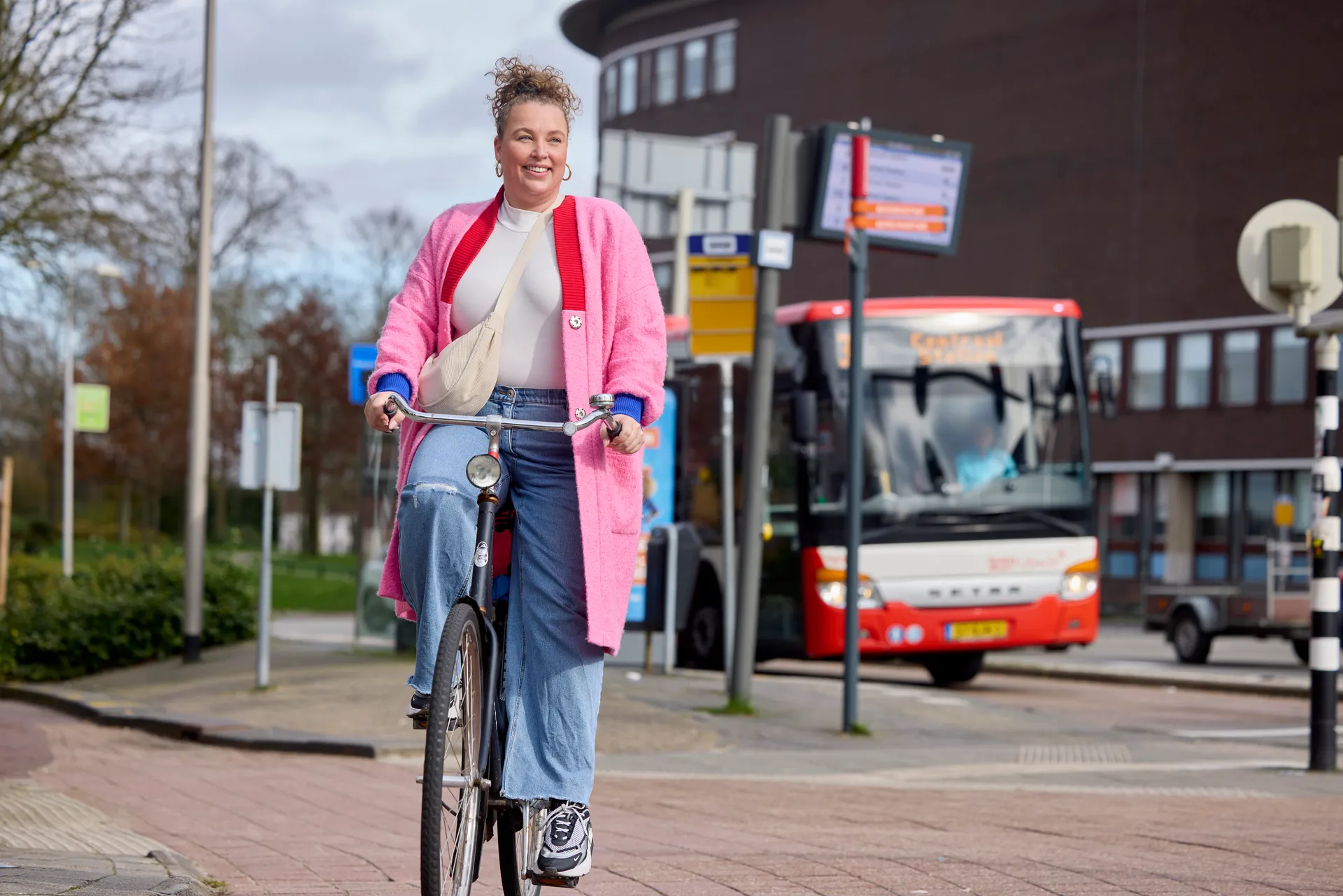 Mevrouw op de fiets in Amersfoort Centrum terwijl er een syntusbus langsrijdt