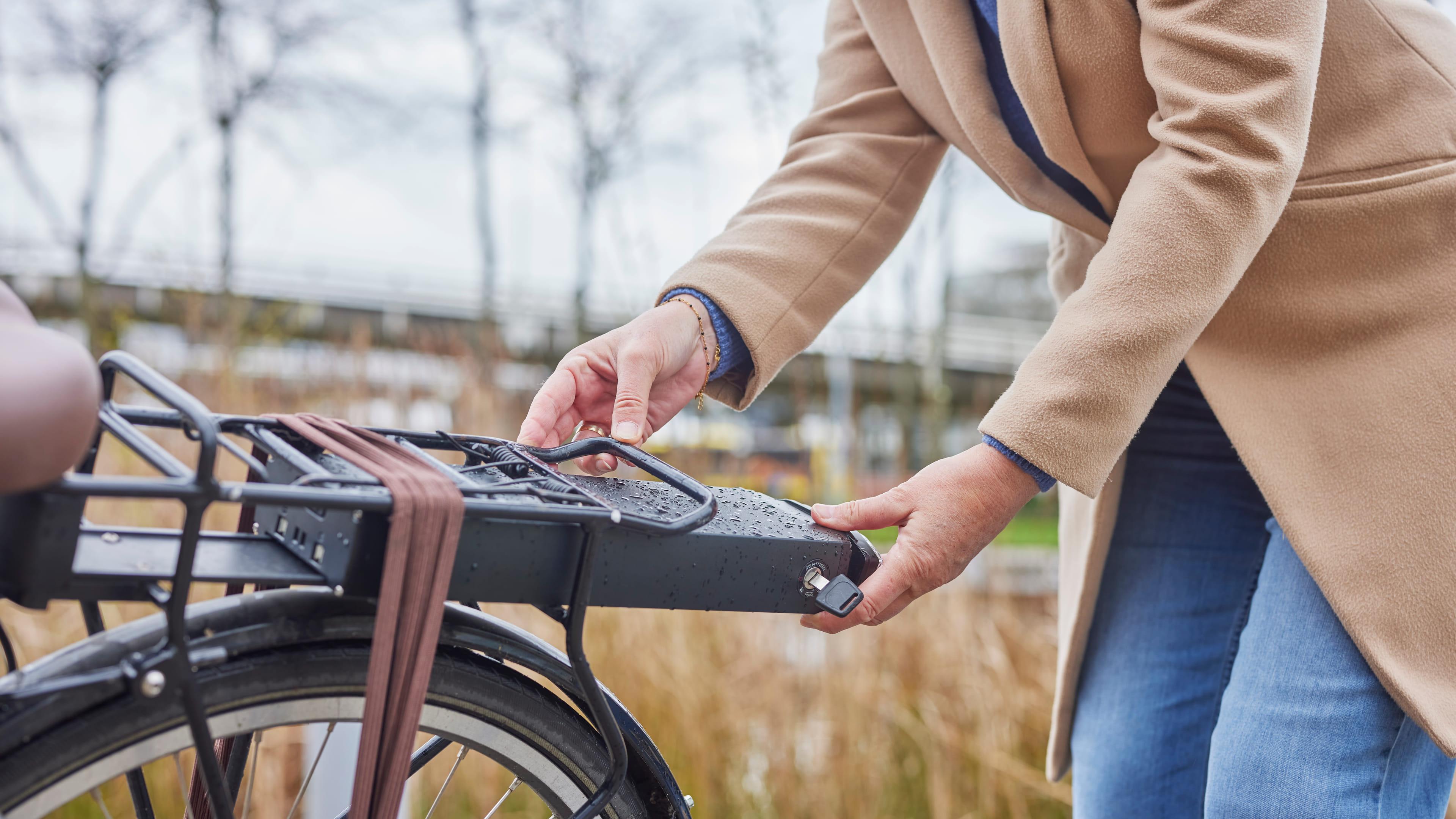 Vrouw is bezig met de accu van haar elektrische fiets.