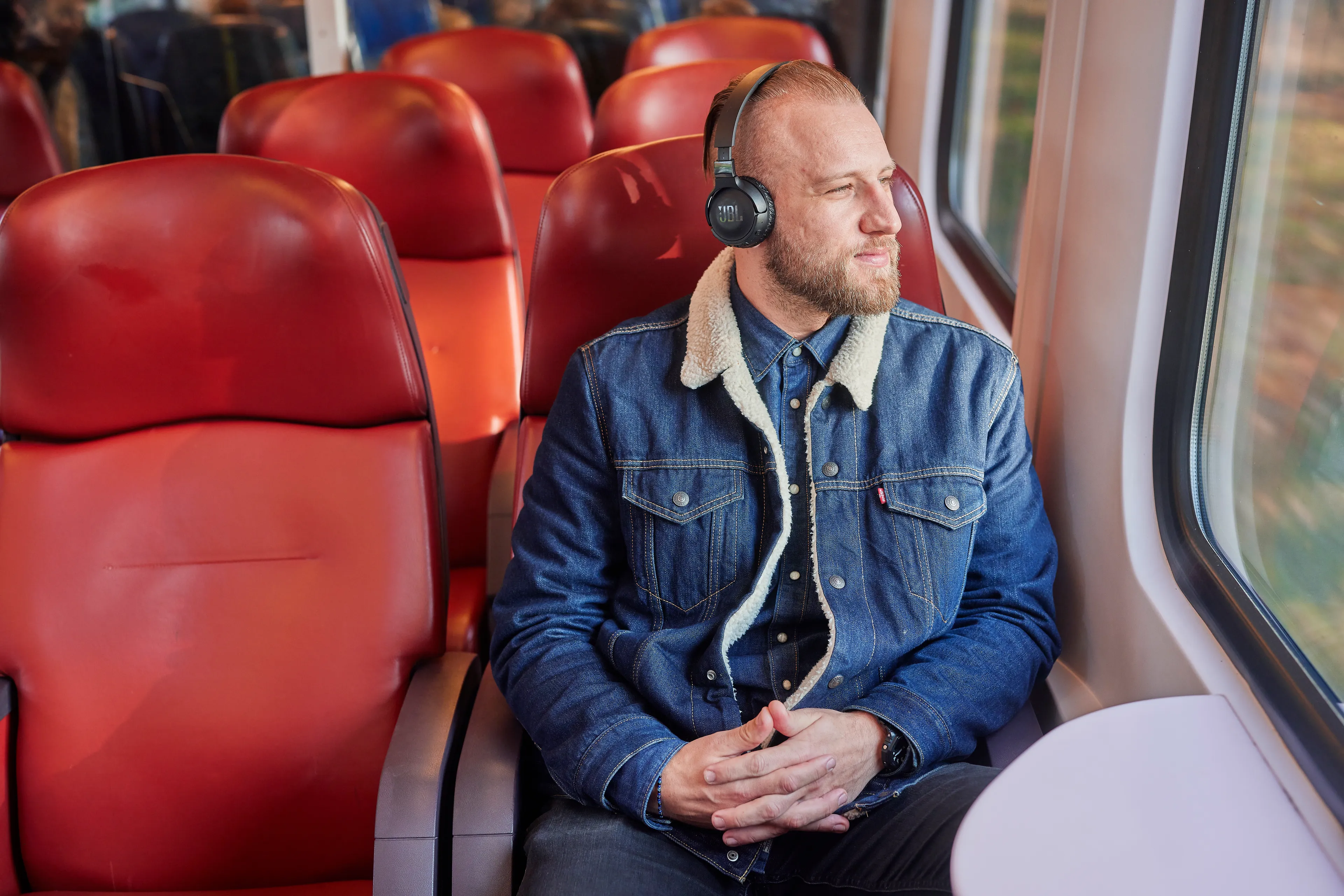 Man zit in de trein terwijl hij muziek luistert en naar buiten kijkt