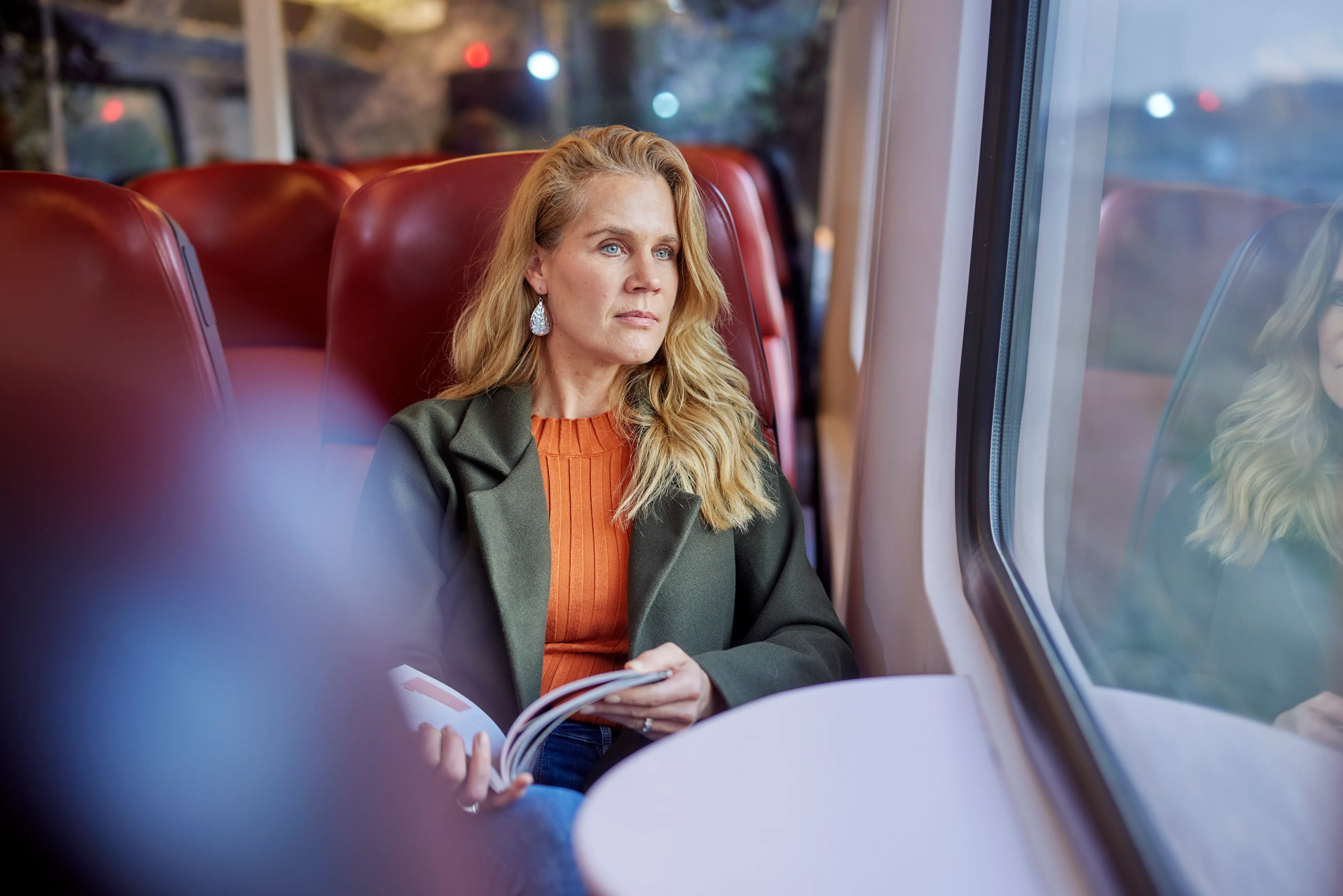 Vrouw die in de trein een boek leest en naar buiten staart
