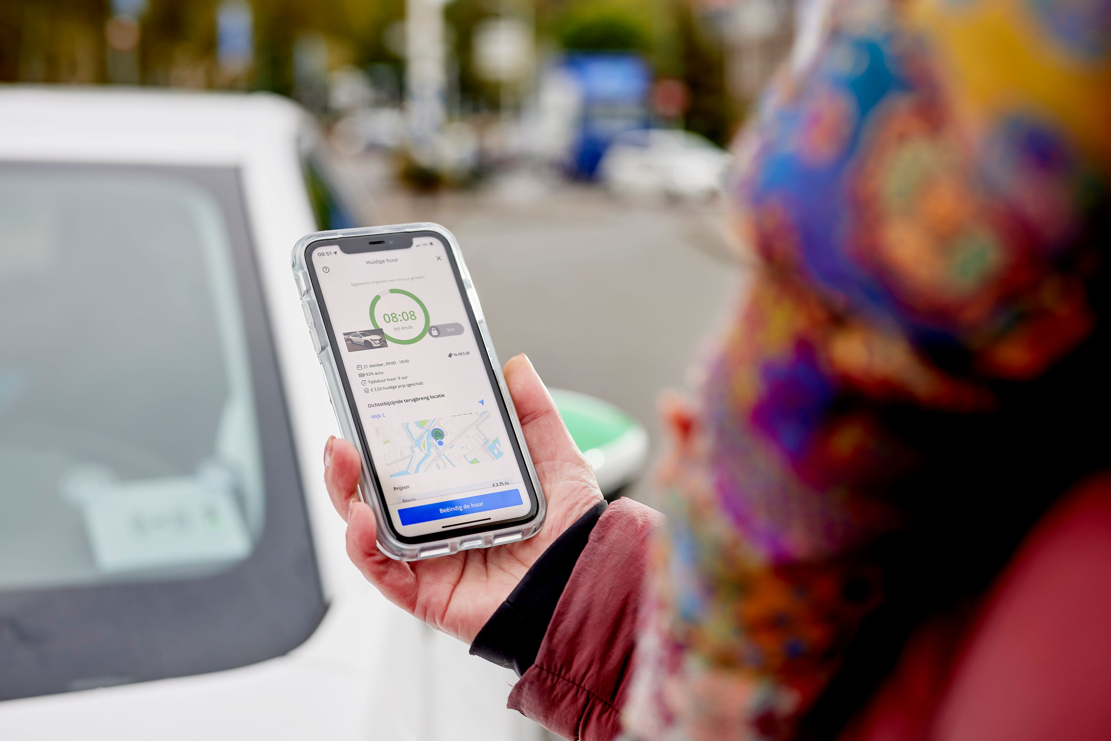Een vrouw opent een deelauto met een app op haar smartphone.